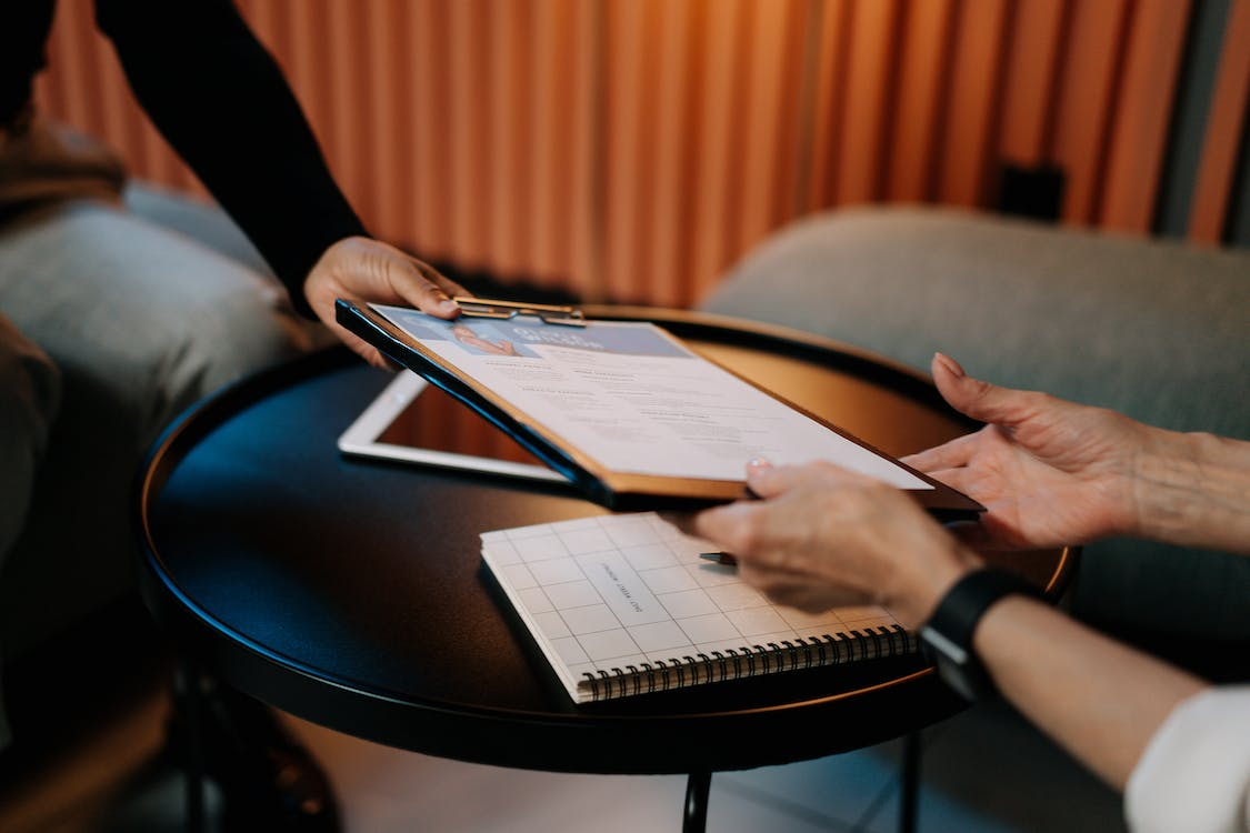 Person in a black long sleeve shirt writing on white paper