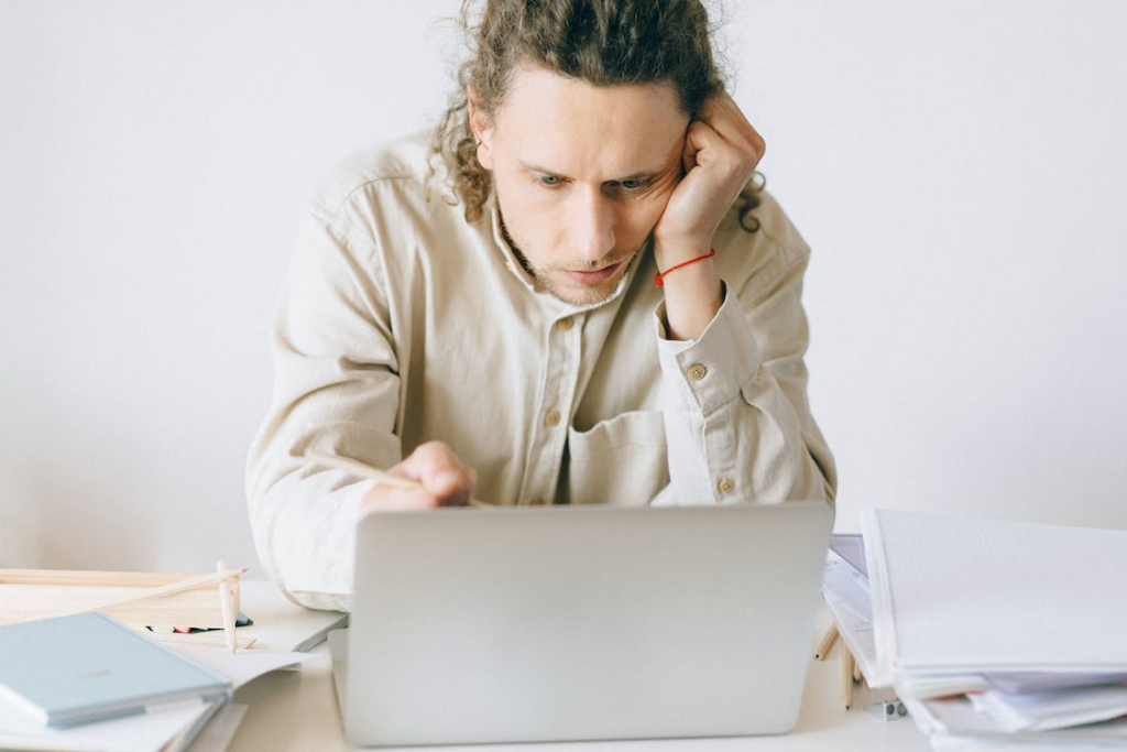 Man in deep thoughts while using a laptop