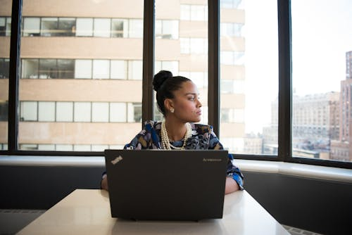 Woman sits in front of a black laptop computer